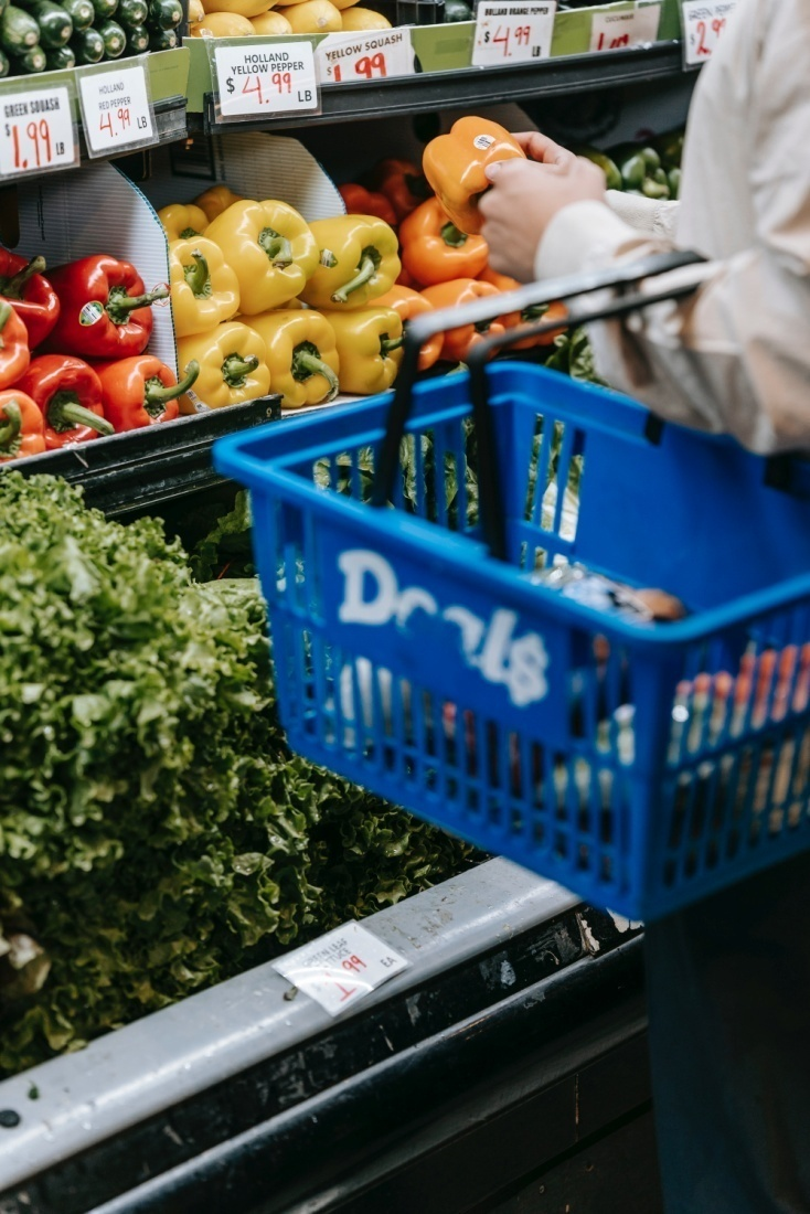 A woman picking out vegetables from a refrigerator 