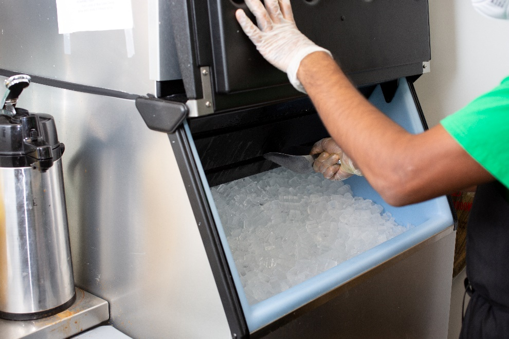 a man wearing gloves scooping out ice cubes