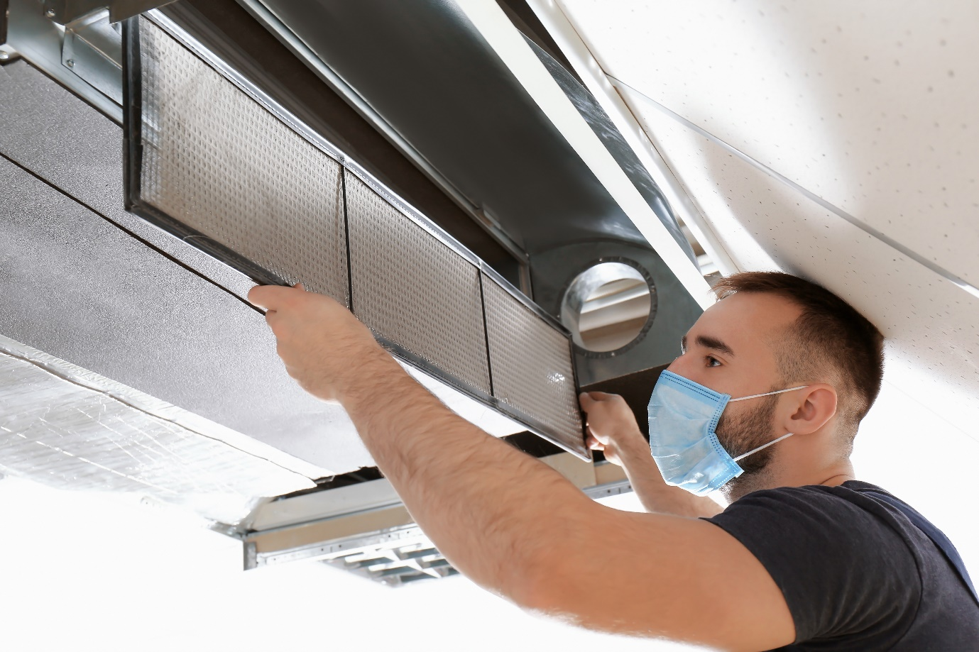 A technician cleaning a commercial air conditioner