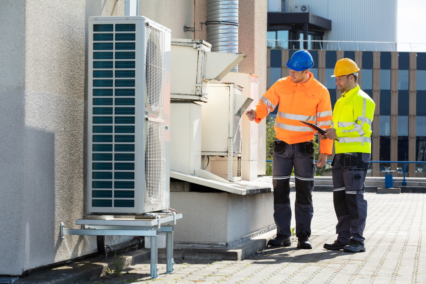 Two technicians checking a commercial air conditioner